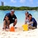 A smiling couple and their 2 young kids build sandcastles on the beach using pails and shovels